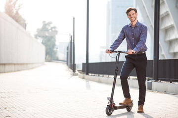 Pleasant smiling man riding a kick scooter © zinkevych