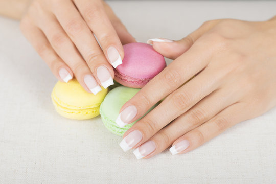 Girl holding colorful macaroons in hands with gel french manicure