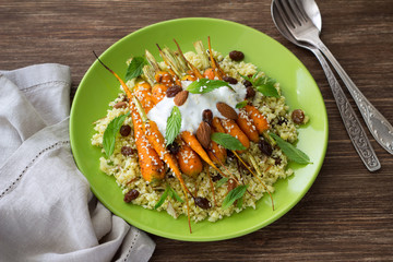 Delicious healthy cauliflower couscous with baked baby carrots, yogurt, sesame, nuts, raisins and...