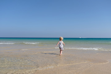 kleines blondes Mädchen rennt am strand