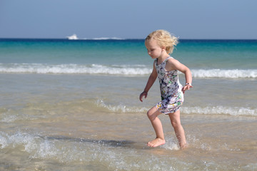 kleines blondes Mädchen rennt am strand