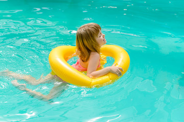 A little girl learning to swim with the help of an inflatable circle