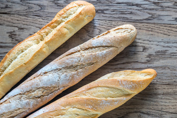 Three baguettes on the wooden background