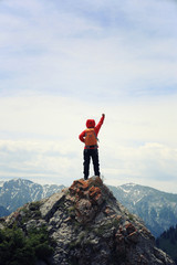 cheering woman hiker open arms on mountain peak