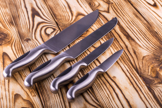 set of shiny metal kitchen knives on a wooden table
