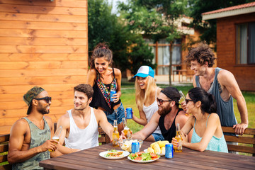 Group of young cheerful friends having fun at picnic outdoors