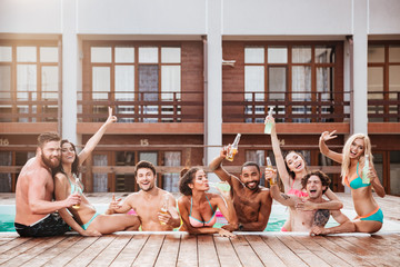 Croup of cheerful happy friends drinking beer at the pool