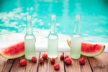 Concept photo alcohol bottles with fresh strawberries halves of watermelon
