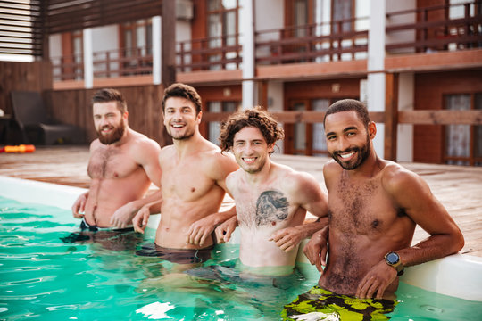 Group of cheerful men standing and relaxing in swimming pool