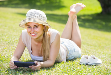 smiling young barefoot woman holding mobile phone in hands