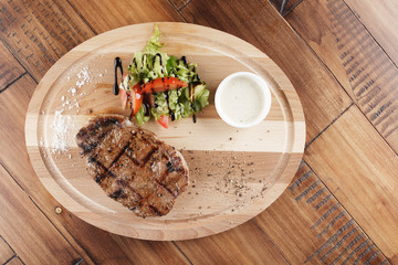 striploin steak with sauce on wooden surface. wooden background.