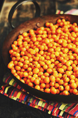 Sea-buckthorn berries in brass bowl on wooden background