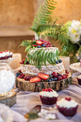 Wedding cake in rustic style with strawberries decorated with fern