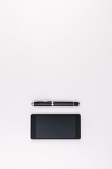 Mobile phone and pen on white background