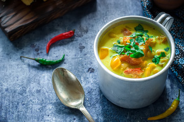 Soup in mug with chick-pea and spices on blue background.