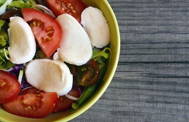 Fresh tomatoes salad with mozzarella cheese,onions,arugula and green lettuce. Healthy eating or vegan food concept.Selective focus.