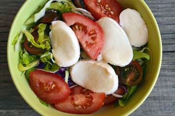 Fresh tomatoes salad with mozzarella cheese,onions,arugula and green lettuce. Healthy eating or vegan food concept.Selective focus.