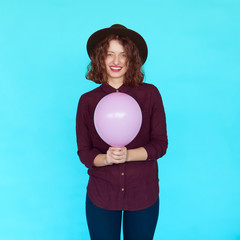 Trendy brunette girl wearing stylish hat, holding a pink balloon