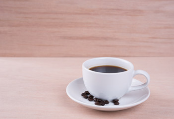 Coffee cup and coffee beans on wood table in coffee shop
