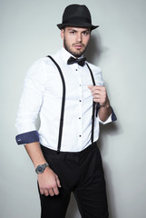 handsome young man wearing hat, suspenders, bow tie and a watch
