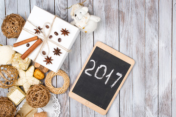 Christmas decoration and gift box over wooden background. Winter holidays concept. 2017 on the tablet.Space for text.