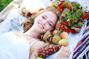 девушка лежит на траве на открытом воздухе, возле девушки много фруктов, счастливая девушка, улыбка