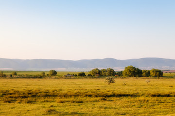 Obraz premium Landscape - field with houses close to hills on a Sunny day in s