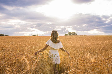 Fototapeta premium Woman with arms outstretched in a wheat field