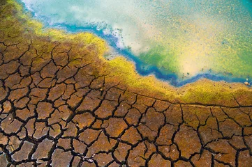 Fotobehang Polluted river water, oil spill, cracked soil during summer drought © Solid photos