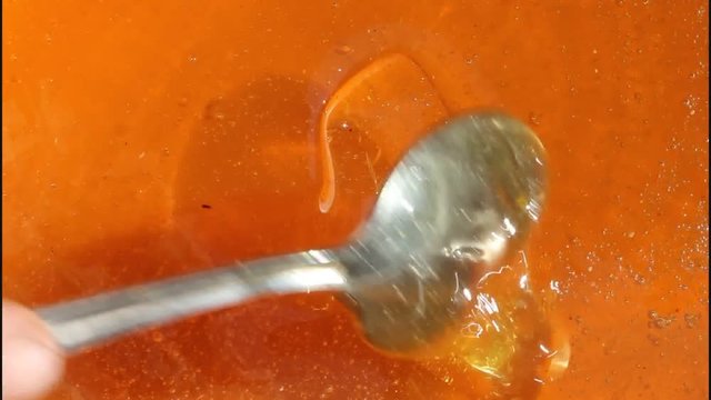 Honey in a vessel stirred with a spoon. It formed air bubbles and swirls.