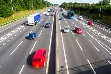 Looking down from above onto the busy carriageways of a motorway or highway that is full of...