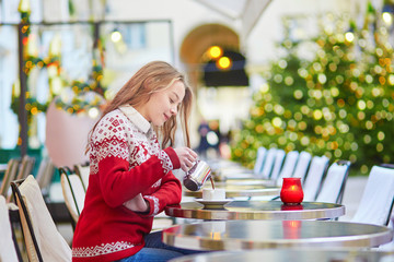 Young woman on a street of Paris decorated for Christmas