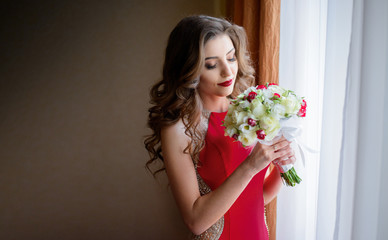 Beautiful bride in red dress holds white wedding bouquet