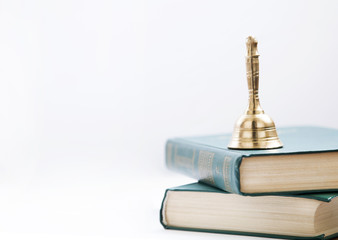 Gold retro school bell on the books, isolated on white background