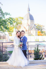 Blessed wedding couple pose on the bridge before old cathedral