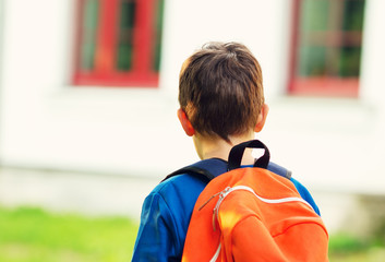 Boy with rucksack infront of a school building. Child with a backpack