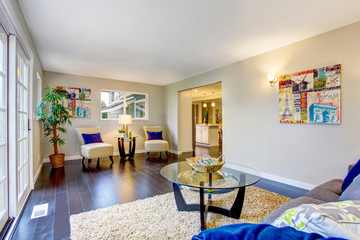 Living room with hardwood floor, beige rug and modern furniture.