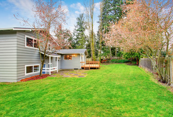 Fototapeta na wymiar Two story house with wooden walkout deck. Fenced backyard