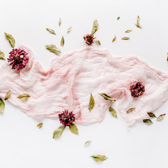 decorated composition with dry red roses, petals and pink textile on white background. flat lay, top view