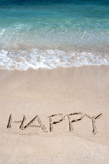 The word Happy drawn on a tropical beach