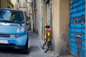 Orange bicycle and blue car on the street in Italy