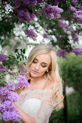 Stunning blonde bride stands with closed eyes before the branche