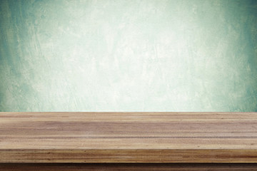 Empty wooden table over green cement wall  background