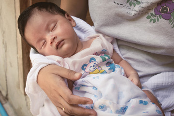 Cute newborn sleeping in mother's arms,vintage