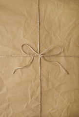 A full page of creased brown parcel paper texture with string bow