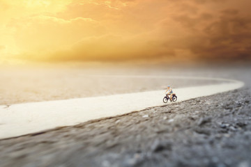 An old man (miniature) on cycle ride in country road y.Soft Focus and Shallow Depth of Field Composition with Soft Pastel Color Theme.