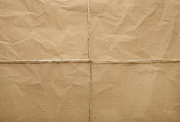 A full page of creased brown parcel paper texture with string tied around it