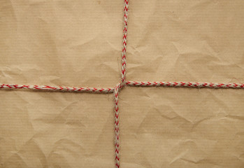 A full page of creased brown parcel paper texture with red bakers twine tied around it