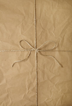 A full page of creased brown parcel paper texture with string bow