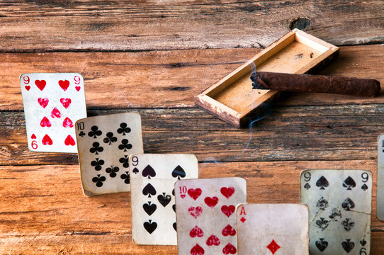 Playing cards and cigar on wooden table